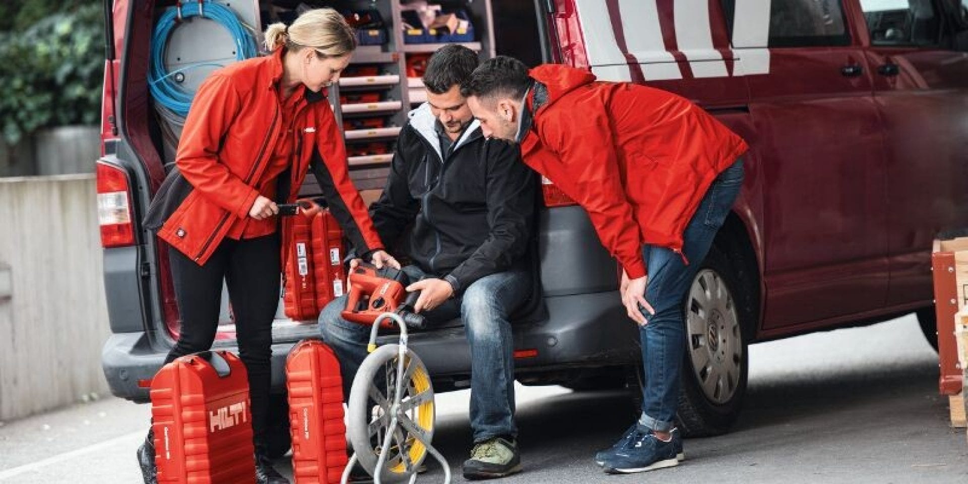 two Hilti employees help a customer with a cordless hammer drill