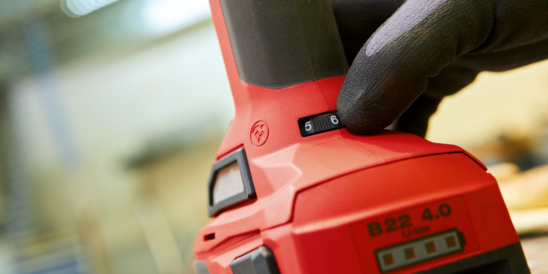 Hilti battery on cordless tool, gloved hand moves the tool's dial